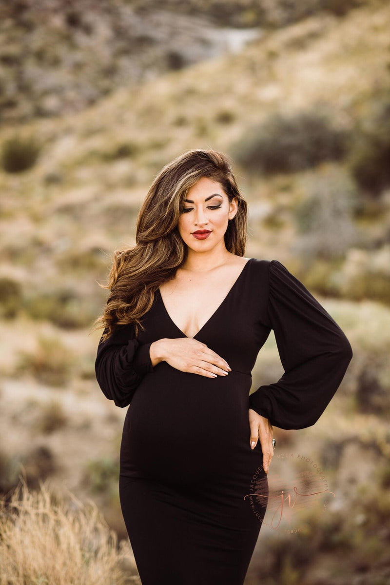 Pregnant woman wearing the Florence gown in black by Sew Trendy standing in desert at sunset