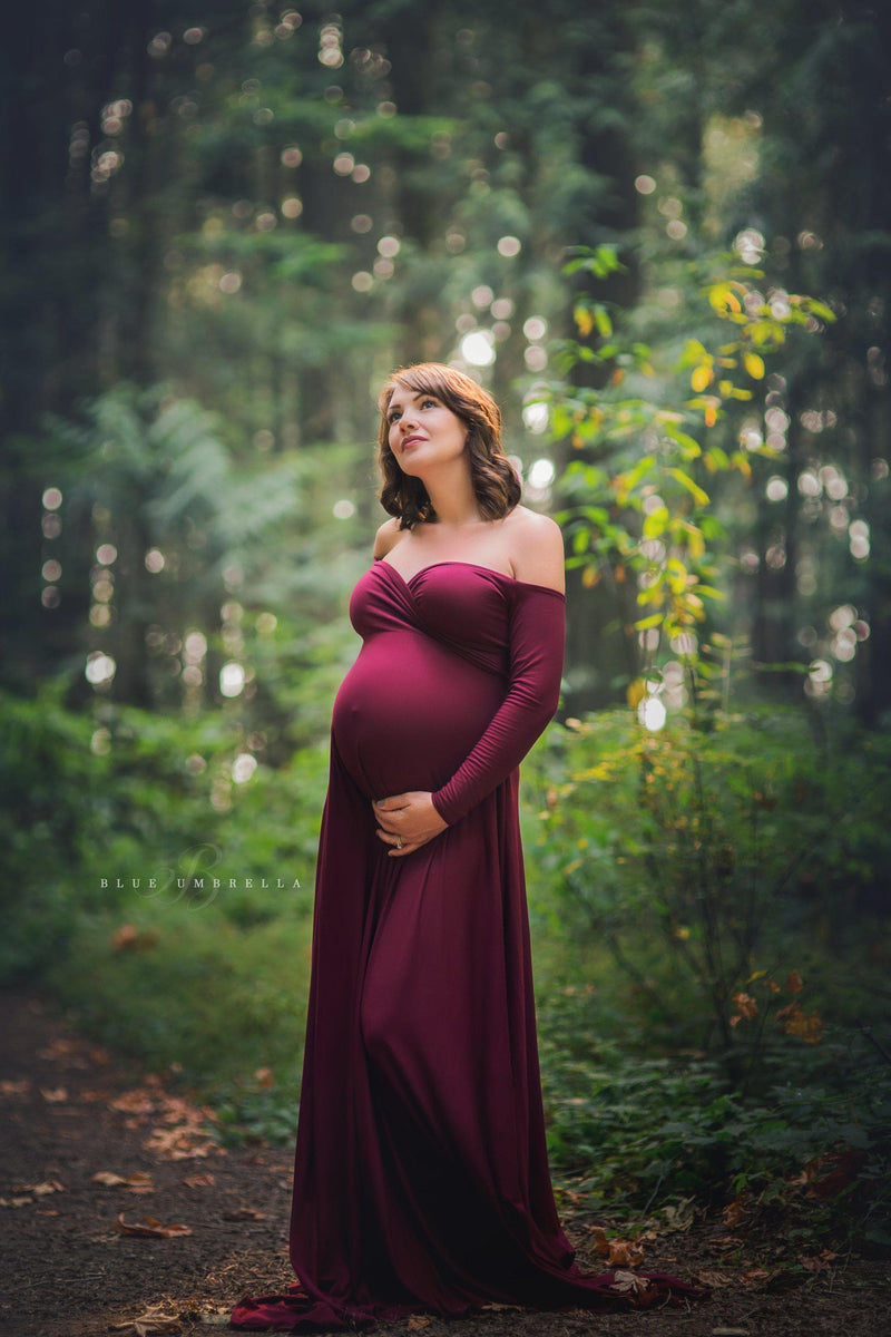 Pregnant woman wearing the Bree gown in burgundy by Sew Trendy standing in green forest