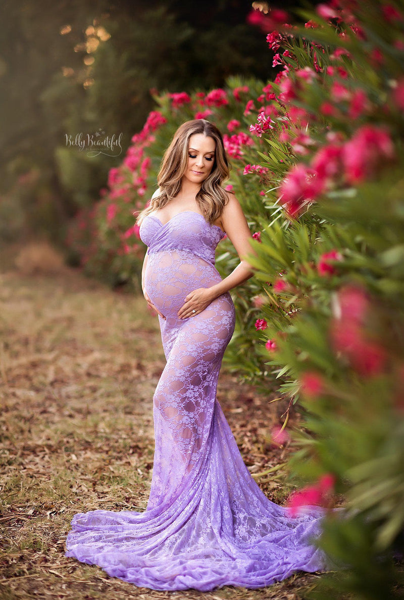 Expecting mother wearing the Catherine gown in lilac by Sew Trendy standing by tropical flower garden