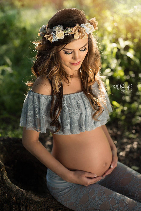 Expecting mother wearing the Casey lace maternity crop in blue rain sitting on a wood stump