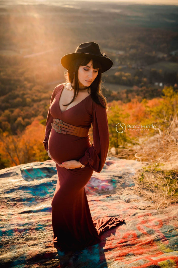 Pregnant woman wearing the Florence gown in redwood by Sew Trendy standing on grafitti rock at sunset