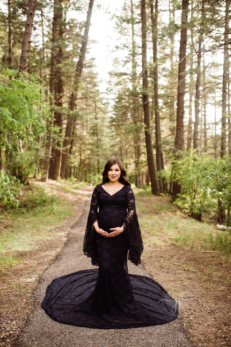 Pregnant mother in the Kenra Gown in black by Sew Trendy Accessories in a forest with tall trees.