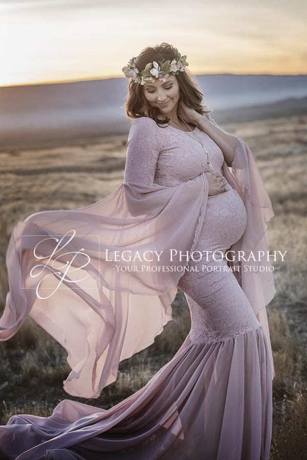 Expecting mother wearing the Angora gown in mauve by Sew Trendy, standing in field at sunset.