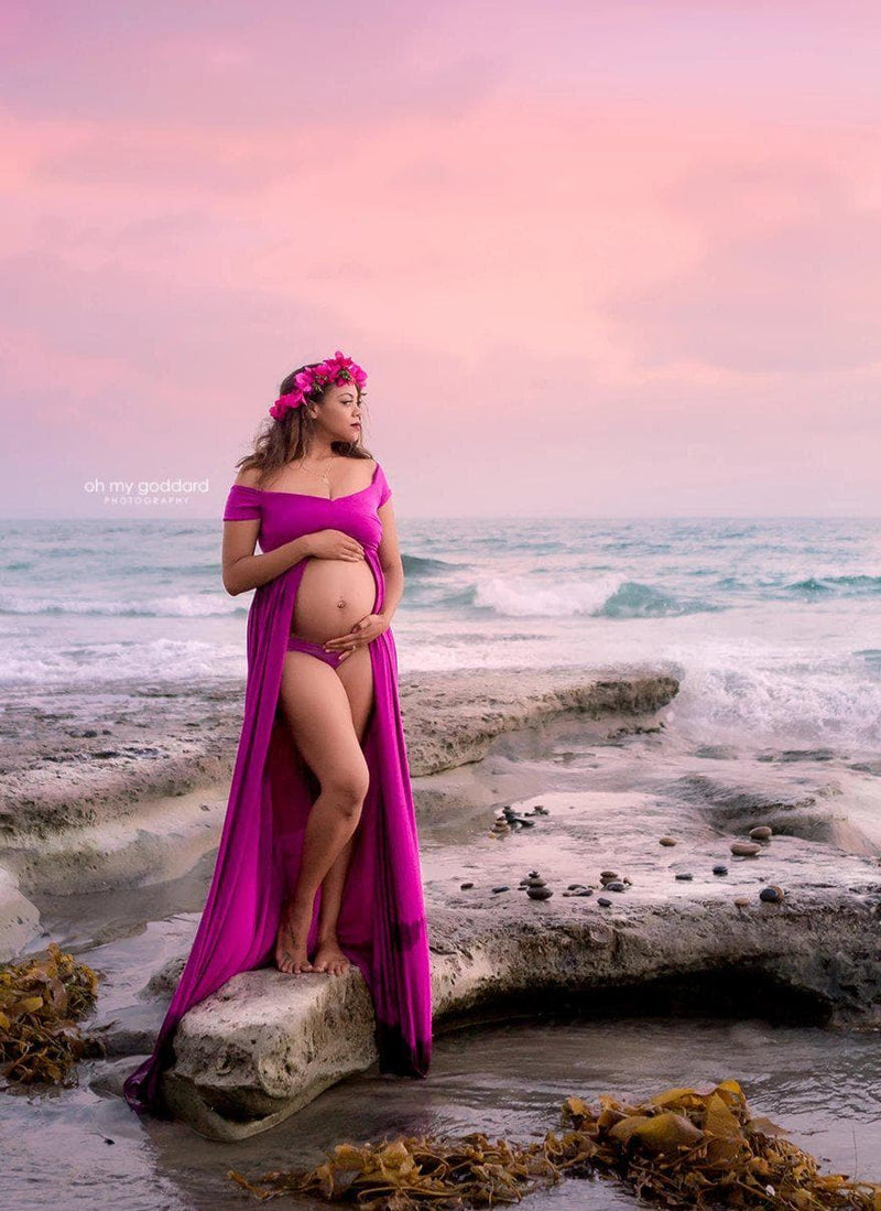 Pregnant Mother in the Kiara gown by Sew Trendy Accessories in Magenta standing on the beach.