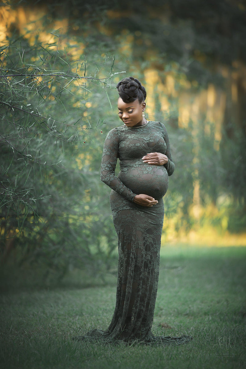 Pregnant woman in the Phoebe Gown in Evergreen by Sew Trendy Accessories standing in front of green trees.