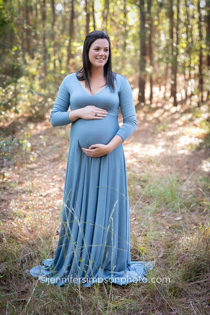 Expecting mother wearing Vanna in steel blue by Sew Trendy standing on forest path