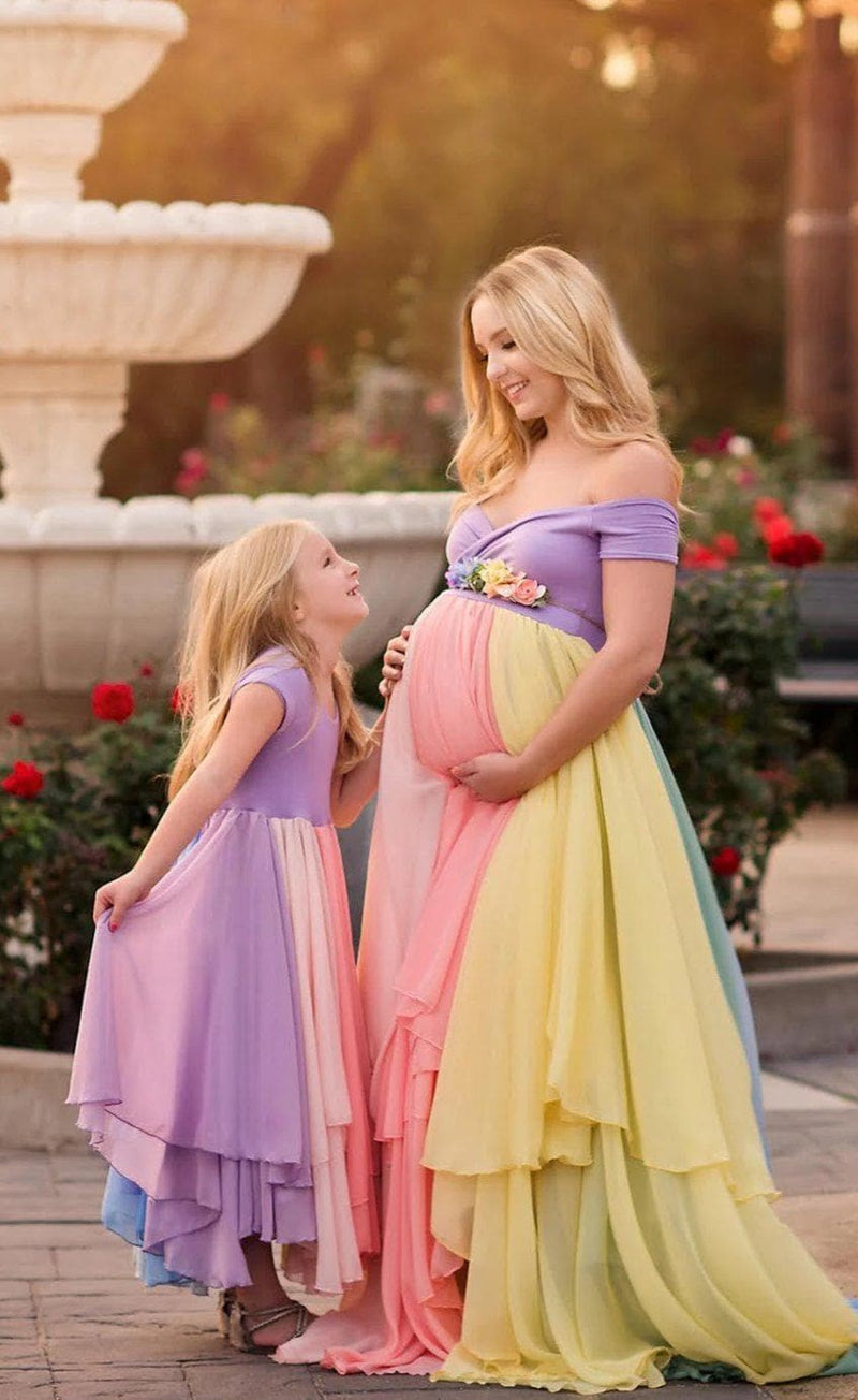 Pregnant mother wearing the Hope Gown in Pastel Tones by Sew Trendy Accessories with flowers and a fountain.