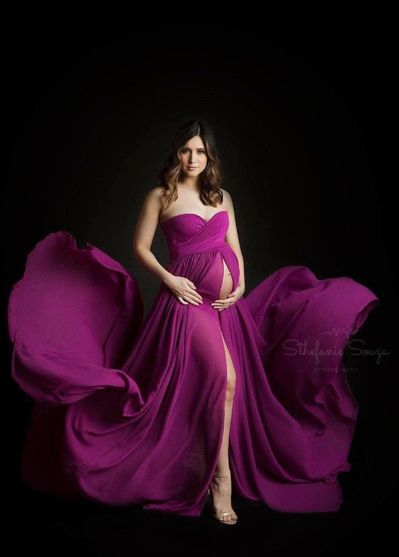 Pregnant woman in the Raquel Gown in Magenta by Sew Trendy Accessories standing in a studio on a black backdrop.