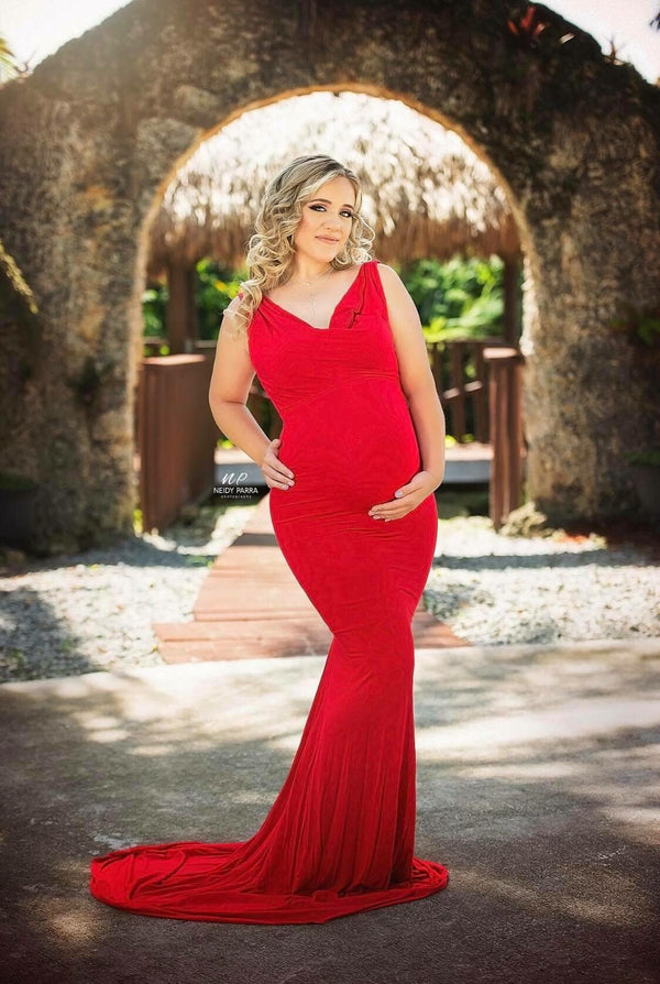 Pregnant woman in the Rue Gown in Red by Sew Trendy Accessories standing in front of a stone archway.