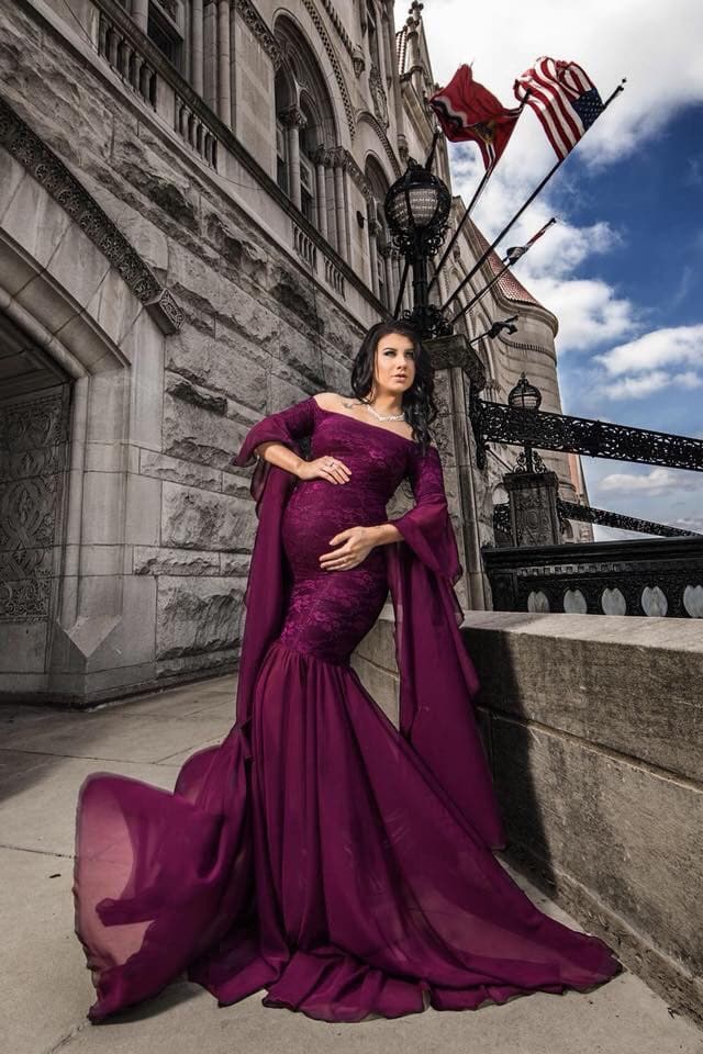Expecting mother wearing angora gown in plum by Sew Trendy, standing in castle.