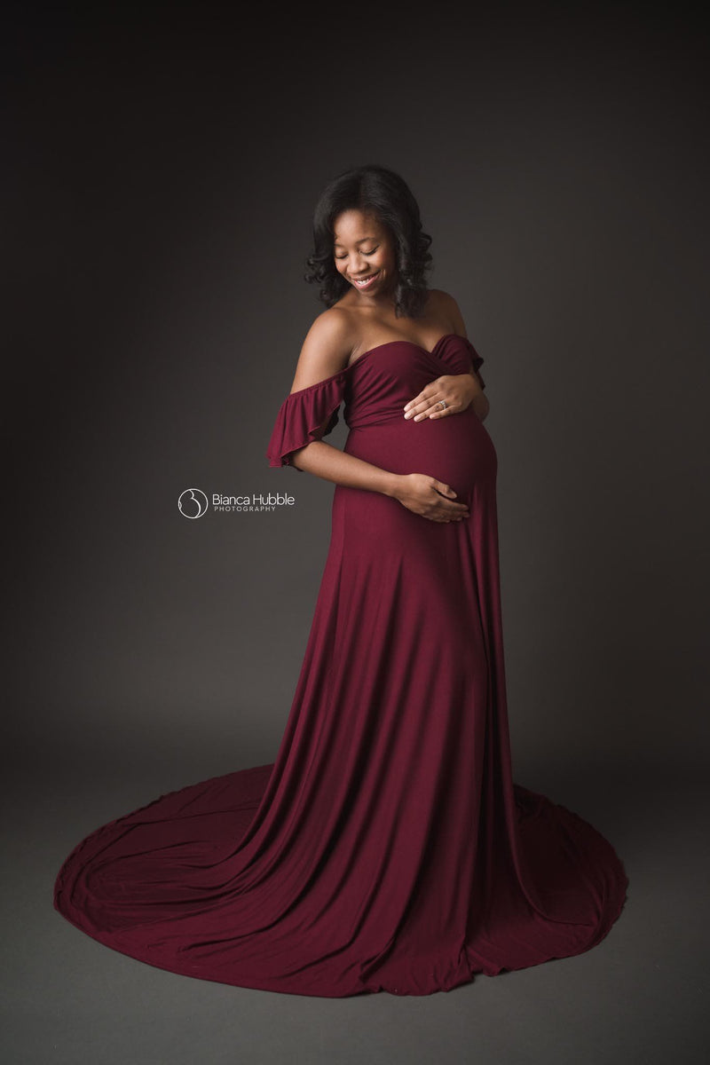 Expecting mother wearing the aspen gown in burgundy by Sew Trendy in studio.