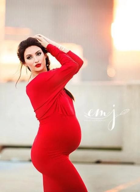 Pregnant mother in the Jaden Gown in Red by Sew Trendy Accessories on a rooftop during sunset.