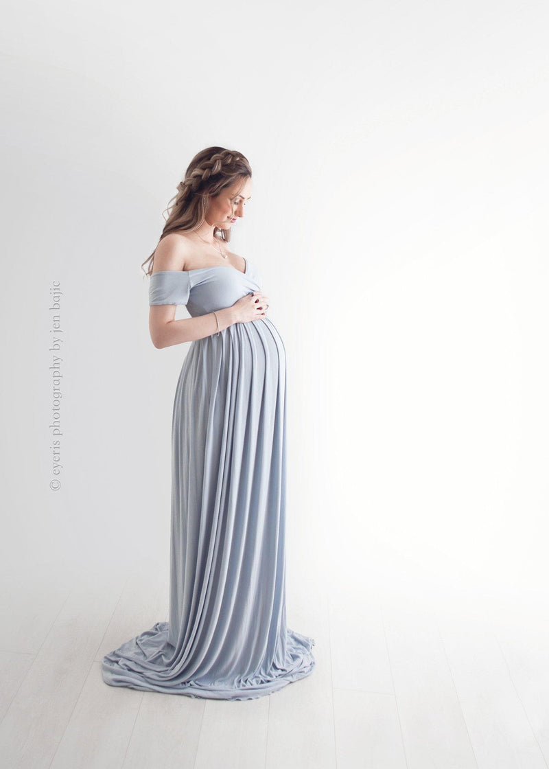 Pregnant Mother in the Kiara gown by Sew Trendy Accessories in grey in a studio with a white background.