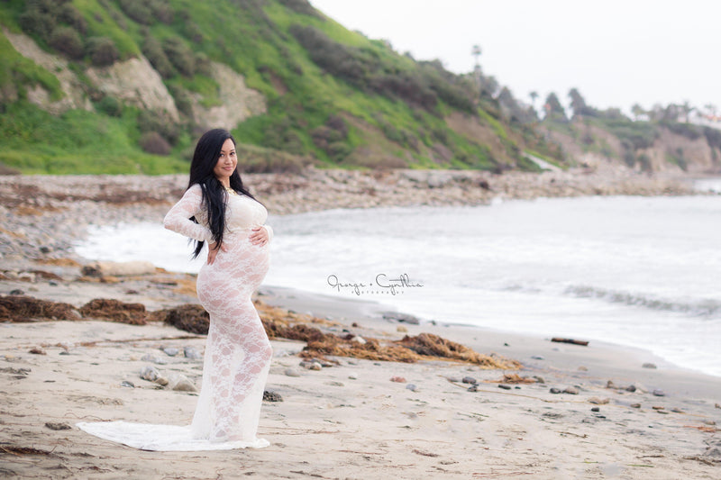 Pregnant woman in the Phoebe Gown in White by Sew Trendy Accessories standing on the beach.