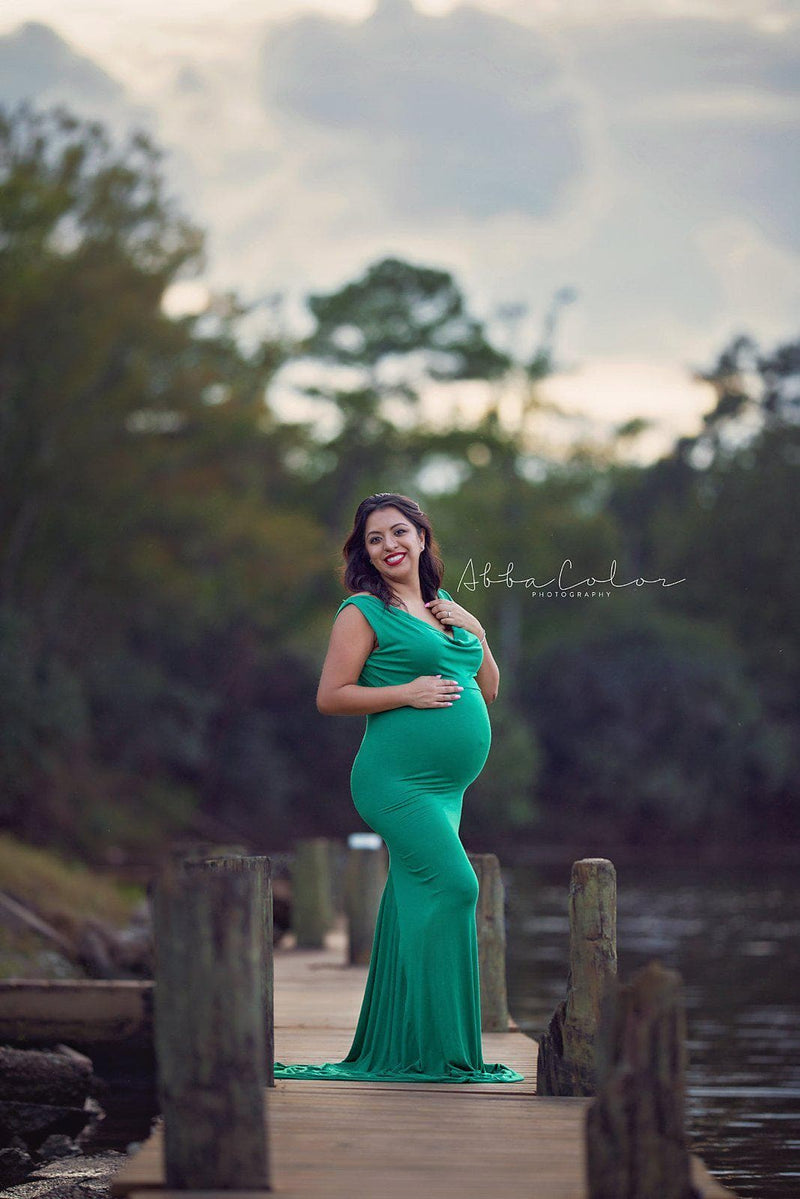 Pregnant woman in the Rue Gown in Emerald by Sew Trendy Accessories standing on a pier.