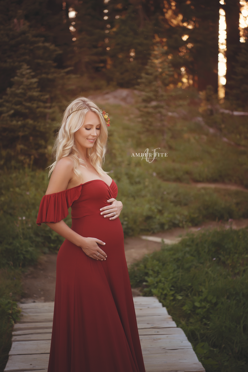 Expecting mother wearing the aspen gown in brick by Sew Trendy standing in Forrest near Mt. Rainier.