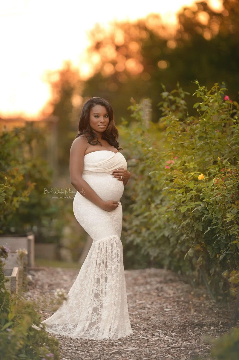 Pregnant mother in the Marilyn Gown in Ivory by Sew Trendy Accessories standing in a garden.