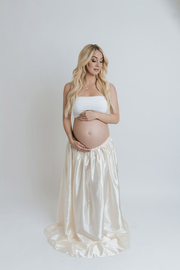 Beautiful pregnant woman wearing the Alma satin skirt by Sew Trendy standing in backlit studio