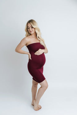 Pregnant woman wearing the Teagan fitted slip by Sew Trendy standing in backlit studio