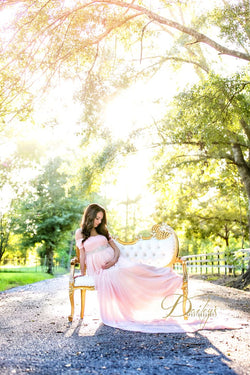Pregnant mother in the Lexcie Gown in Blush by Sew Trendy Accessories sitting in a chair with trees in the background.
