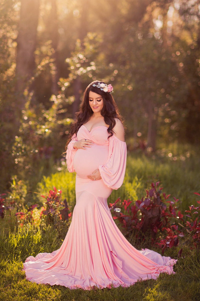 Glowing pregnant woman wearing the Erica gown in dusty pink by Sew Trendy Accessories in a grove of trees.