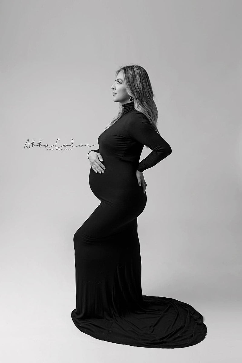 Glamorous Pregnant mother in the Layne Gown in black by Sew Trendy Accessories in a studio with a white backdrop.