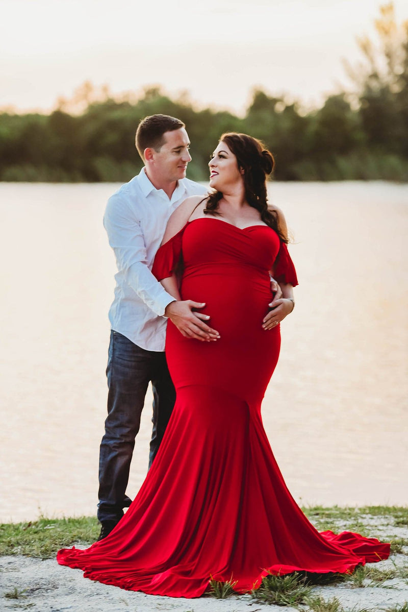 Expecting mother wearing the Serenity in red by Sew Trendy standing with husband near lake