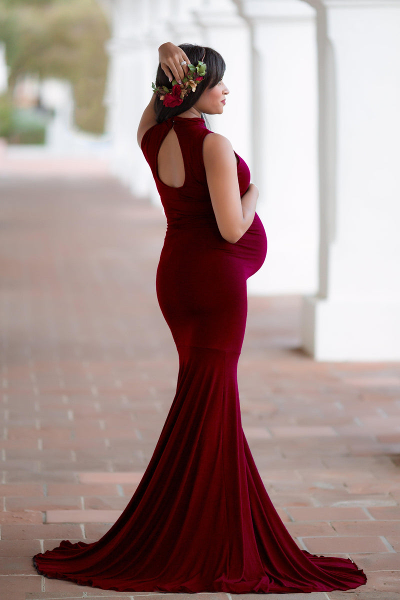 Pregnant woman in the Allesandra gown by Sew Trendy standing in an urban entryway