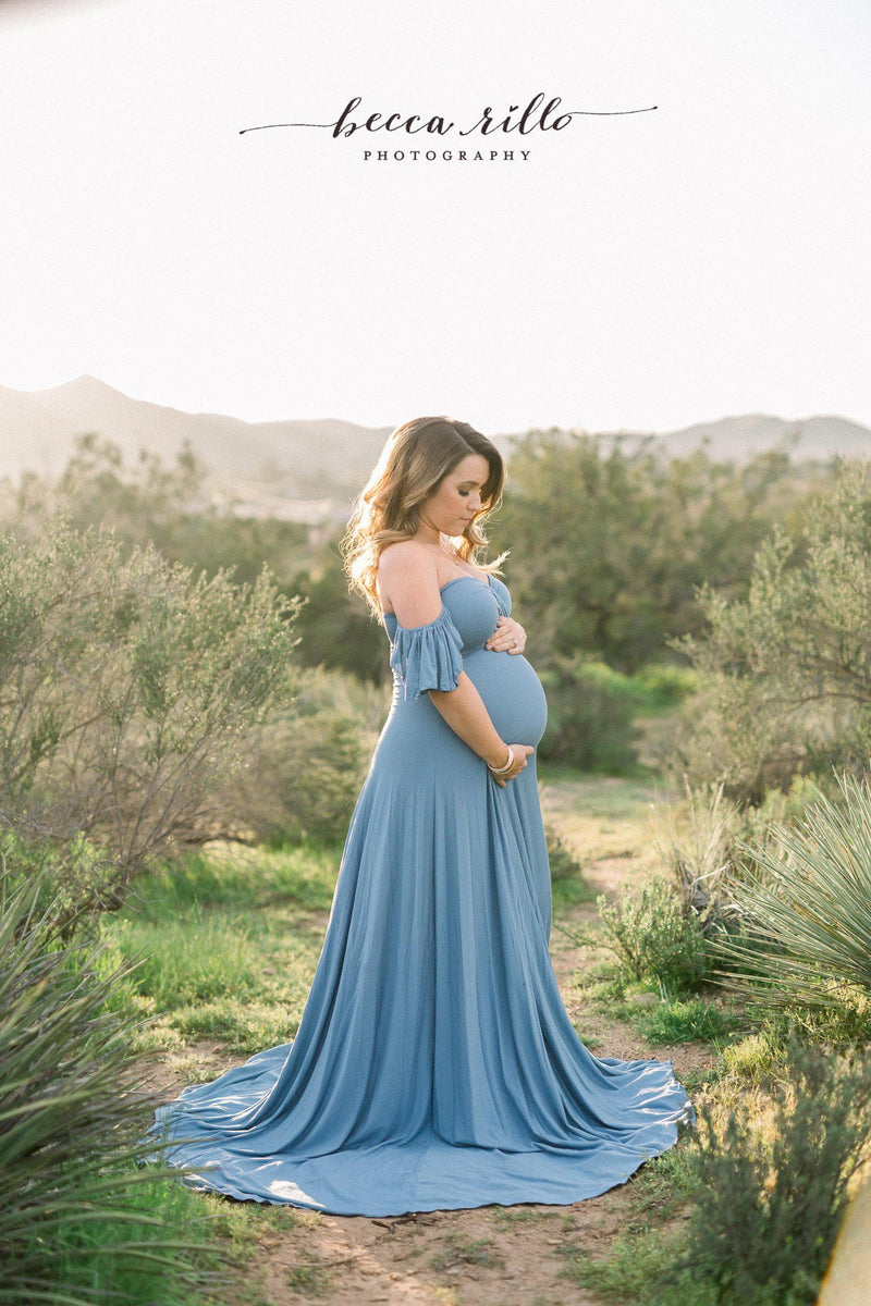Expecting mother wearing the aspen gown in steel blue by Sew Trendy standing in California desert.