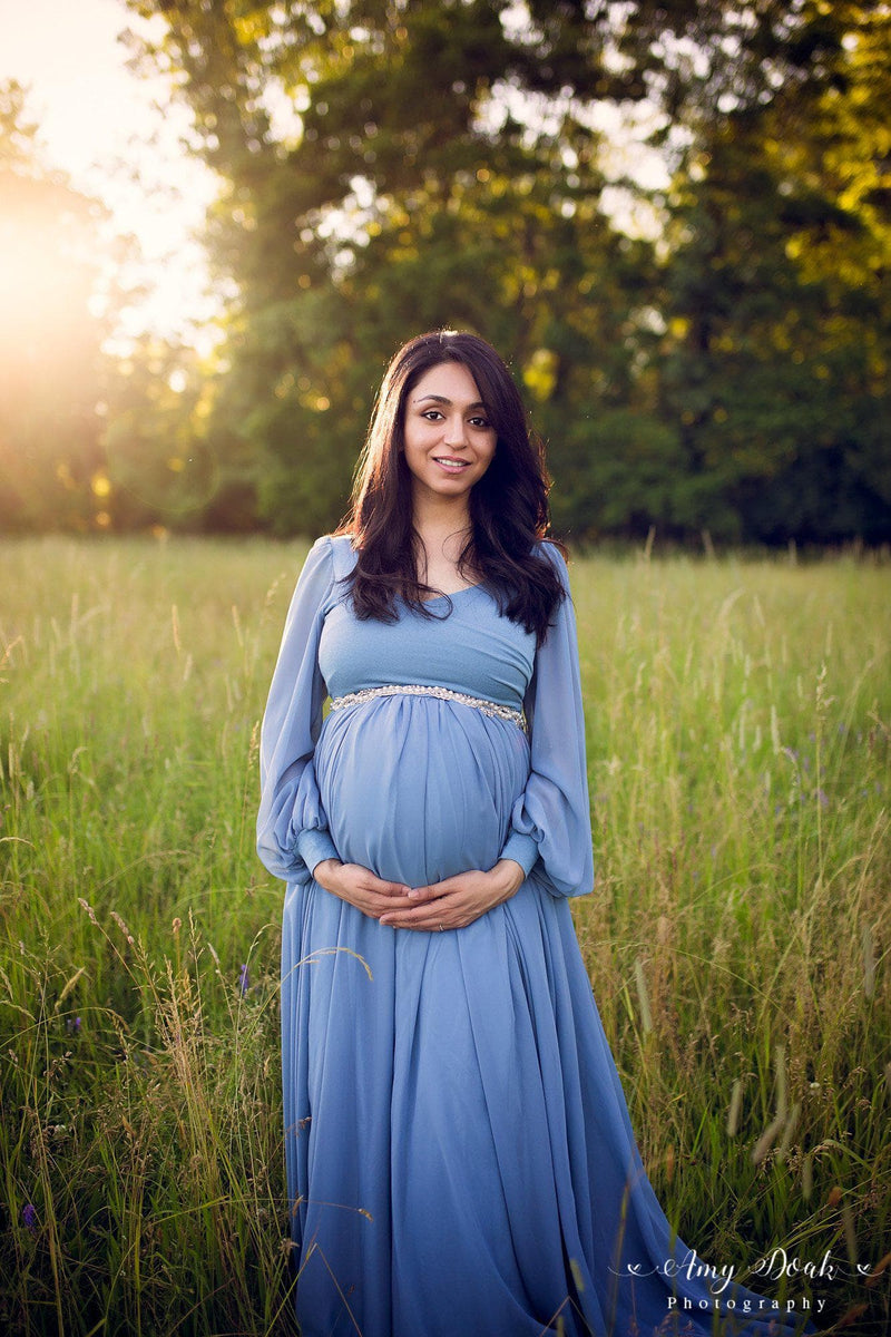 Pregnant mother wearing Brigitte gown in steel blue by Sew Trendy standing in green field