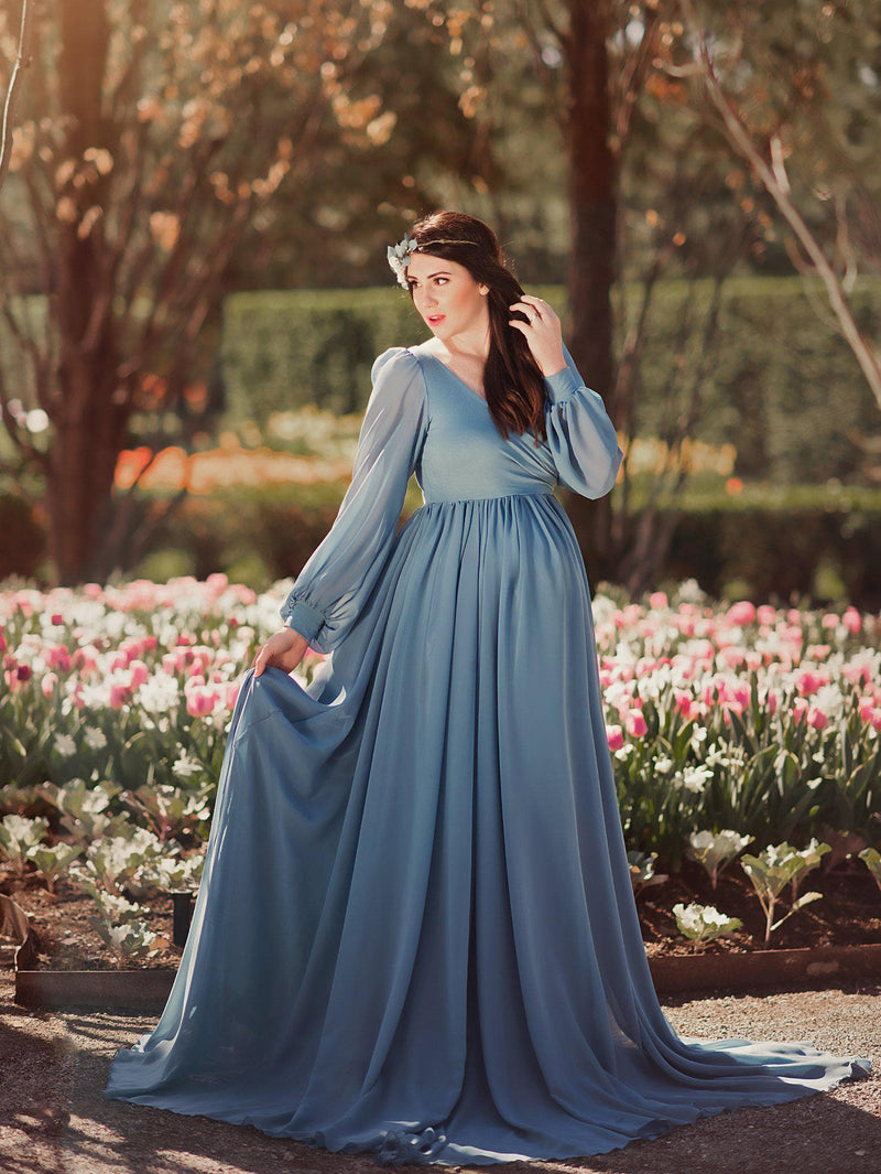 Pregnant mother wearing Brigitte gown in steel blue by Sew Trendy standing in studio on garden