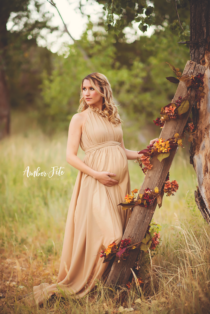 Pregnant woman wearing the Carolynne gown in Camel by Sew Trendy standing on forest path