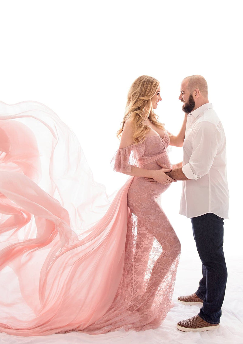 Beautiful pregnant mother wearing the annalise gown and butterfly tossing train standing with her husband in studio
