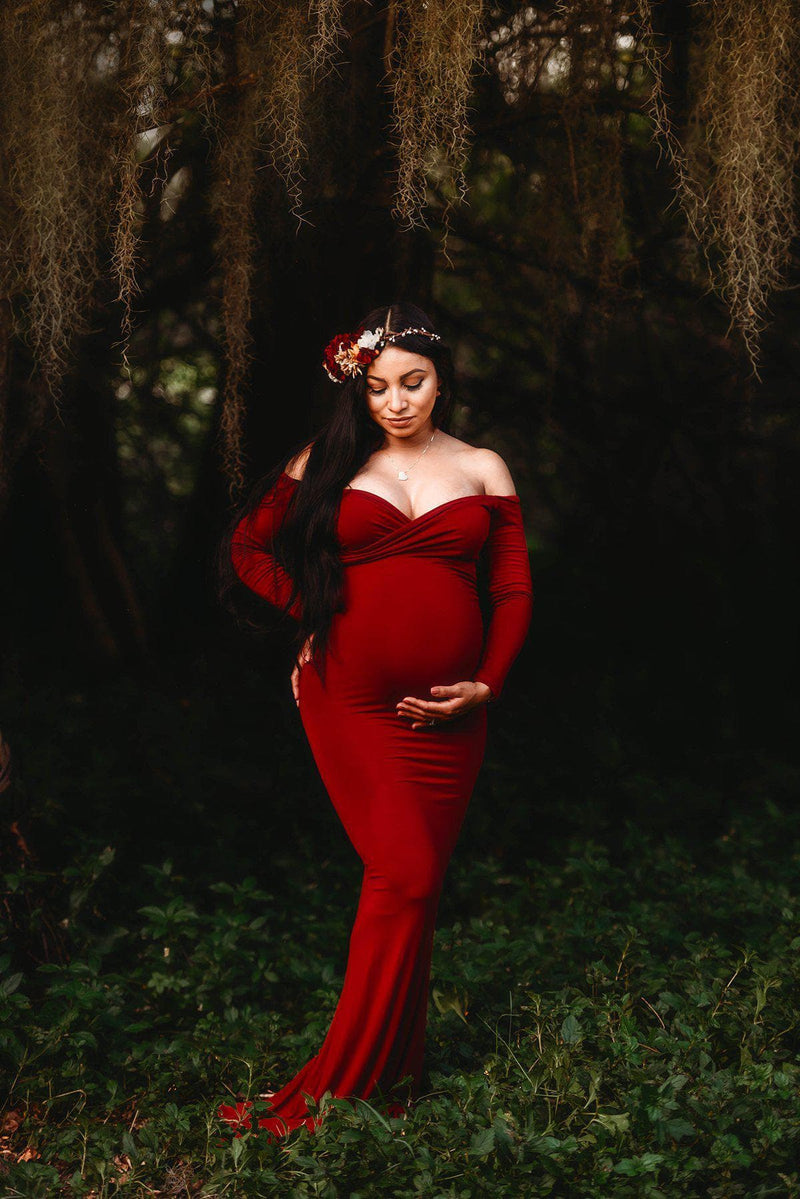 Pregnant woman wearing the Emerlie gown in wine by Sew Trendy standing under willow tree