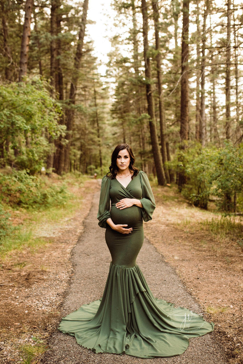 Pregnant mother wearing the Francis gown in evergreen by Sew Trendy standing on a forest path in autumn