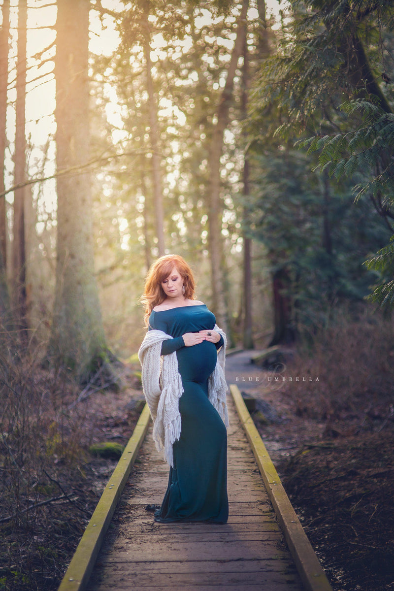Pregnant mother in the Jaden Gown in Teal by Sew Trendy Accessories on a bridge in the forest.