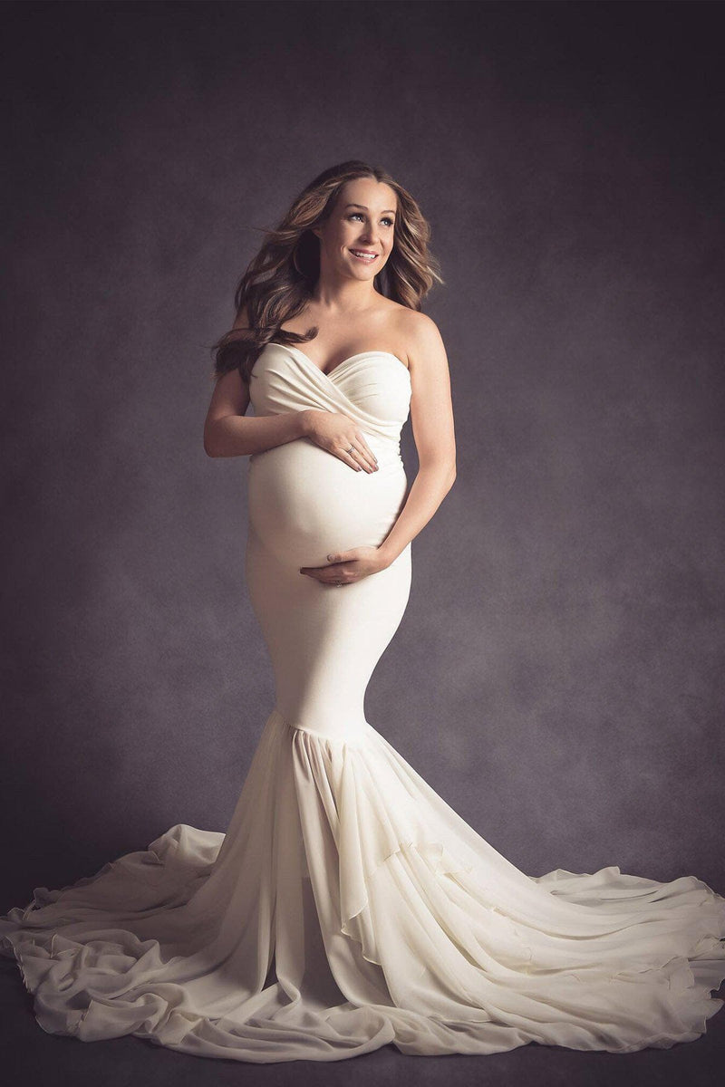 Pregnant mother in the Liv Gown by Sew Trendy Accessories in Ivory in a studio with a dark background.