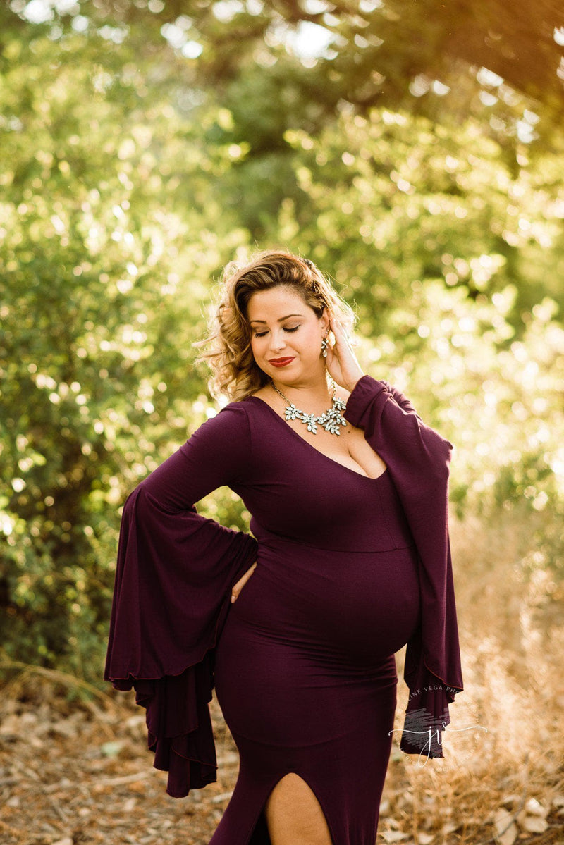 Pregnant mother wearing Veda gown in plum by Sew Trendy standing in sunkissed tree grove