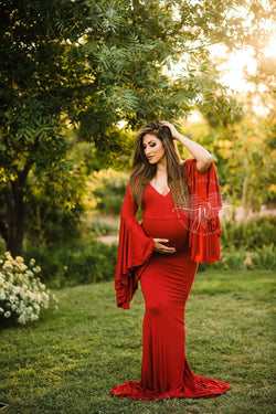 Pregnant mother wearing Veda gown in red by Sew Trendy standing in sunkissed tree grove