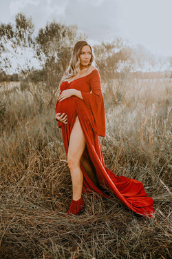 Expecting mother wearing the Wren gown in brick by Sew Trendy standing in a field at golden hour
