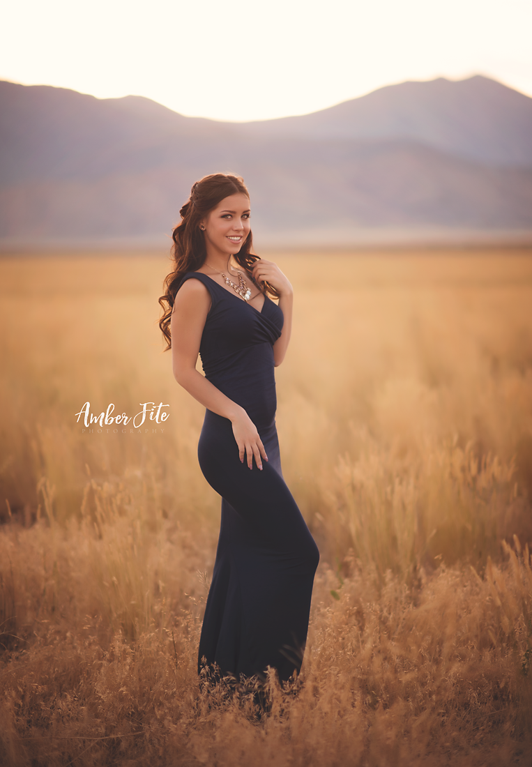 Beautiful brunette model wearing the Courtney gown in navy by Sew Trendy standing in field at dusk
