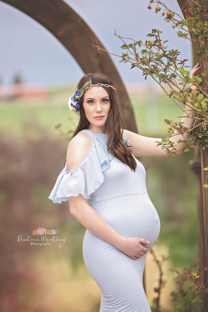 Pregnant woman in the Sariah Gown in Blue Rain by Sew Trendy Accessories with a flower crown.
