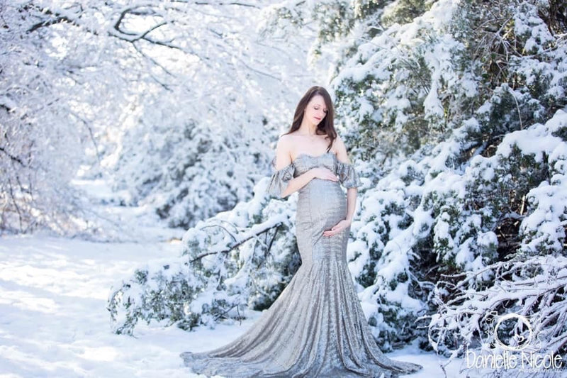 Pregnant woman in the Serenity Gown in Silver Sequin by Sew Trendy Accessories standing in the snow during winter.