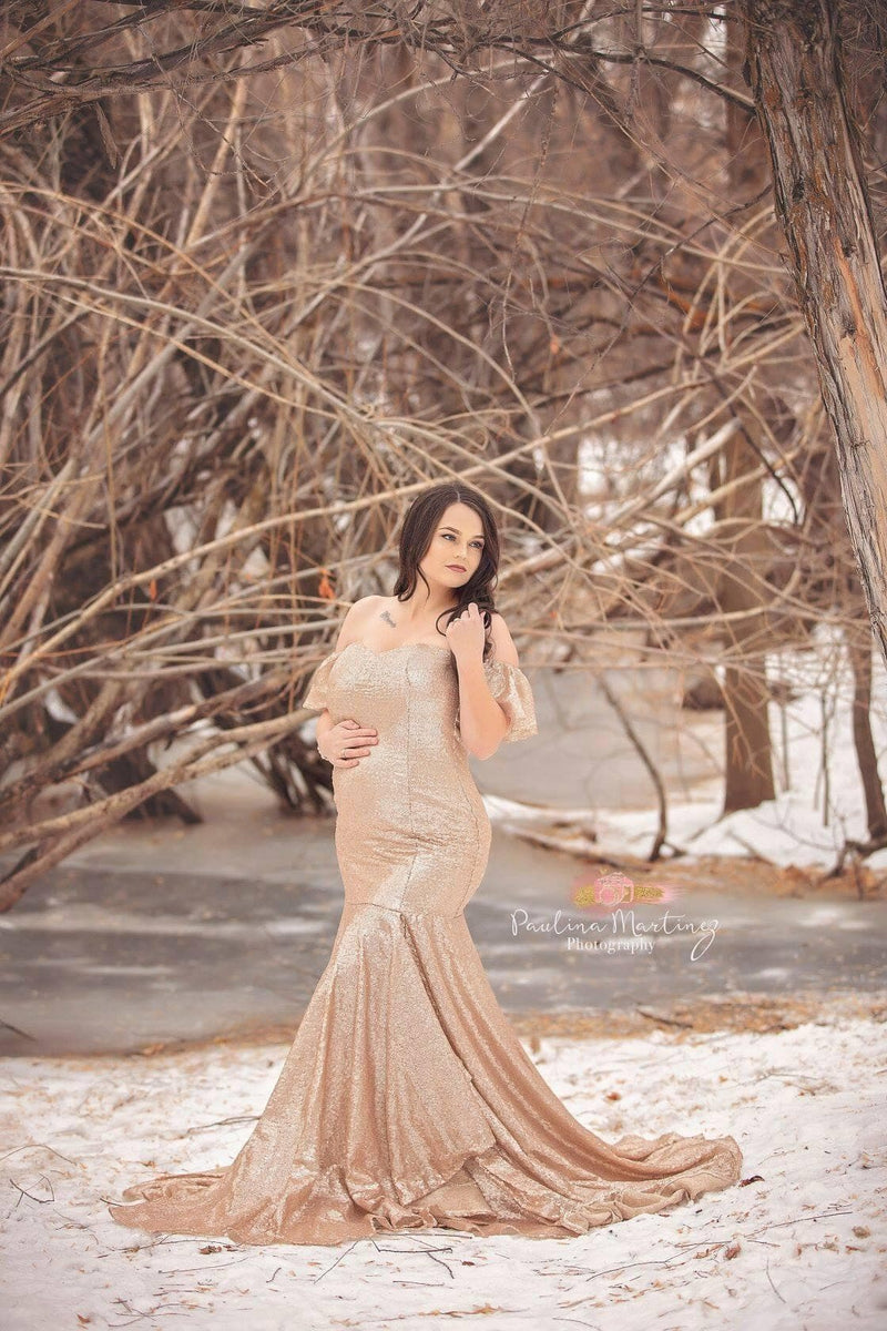 Pregnant woman in the Serenity Gown in Rose Gold Sequin standing in the snow.