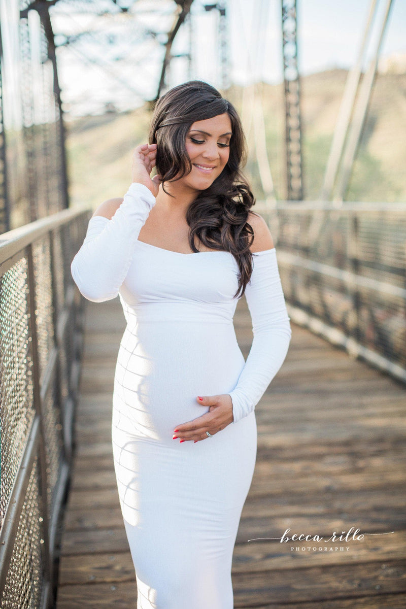Pregnant woman wearing the Emerlie gown in white by Sew Trendy standing on bridge