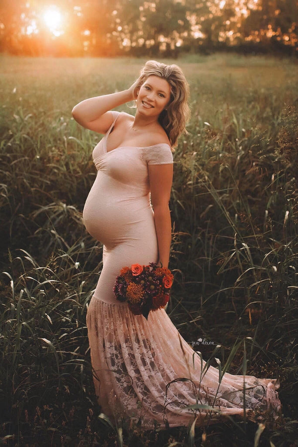 Pregnant woman wearing the bella gown in blush by Sew Trendy standing in sunkissed field.