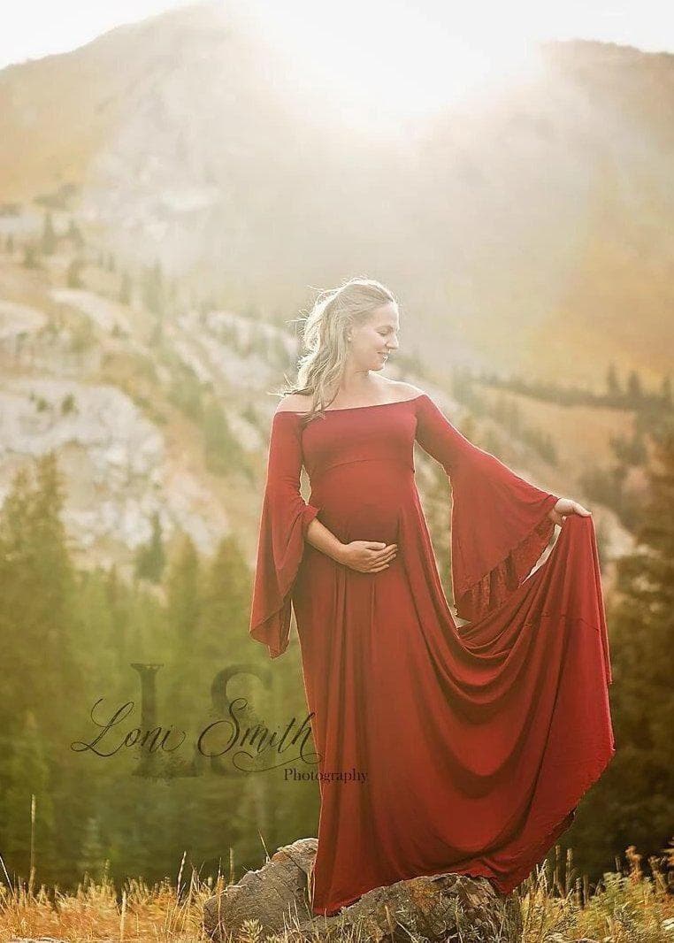 Expecting mother wearing the Gwen gown in brick by Sew Trendy standing on a mountain at golden hour