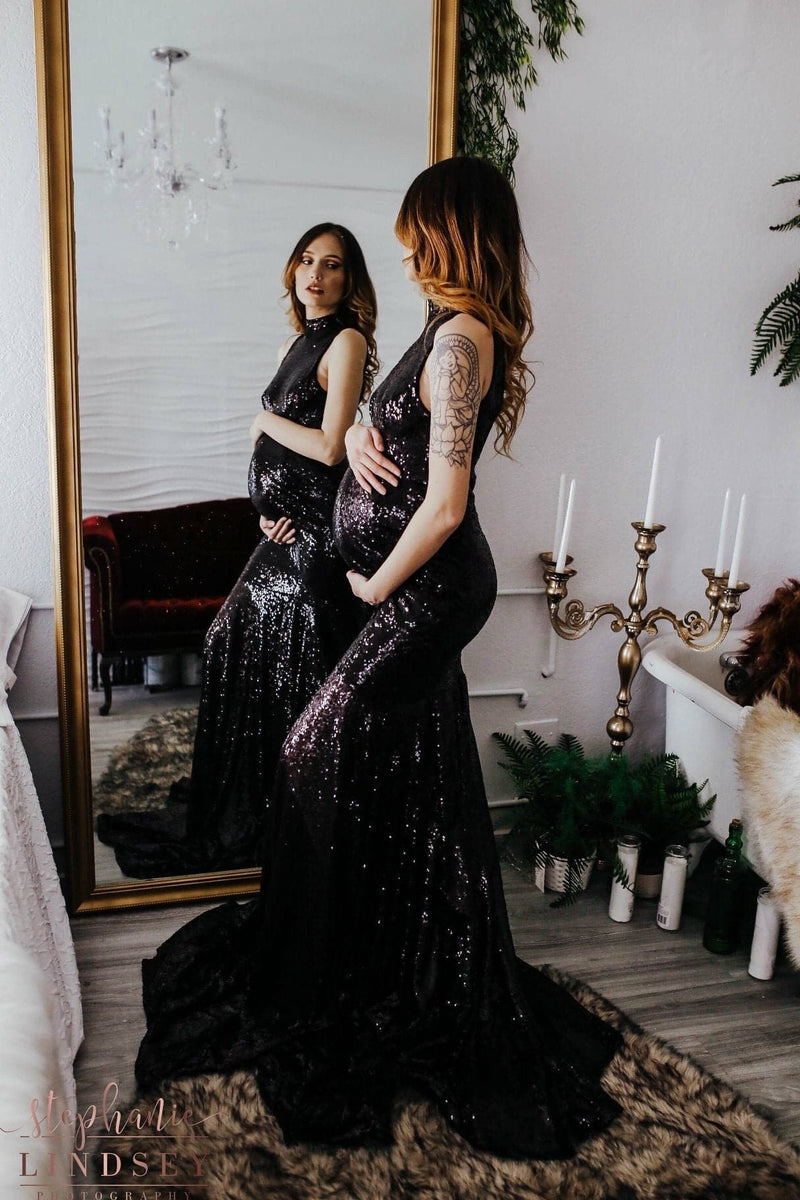 Pregnant woman wearing the allesandra gown in black sequins by Sew Trendy standing in front of mirror in studio