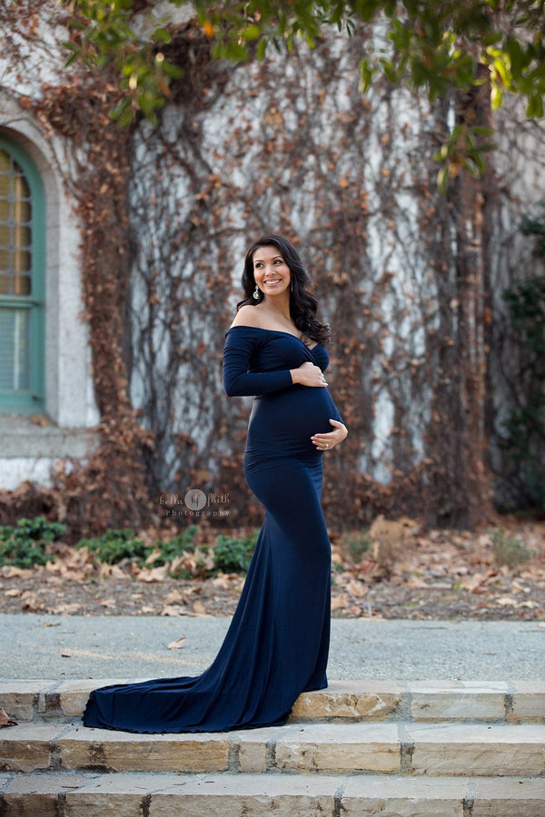 Pregnant woman wearing the Emerlie gown in navy by Sew Trendy standing on stone stairs