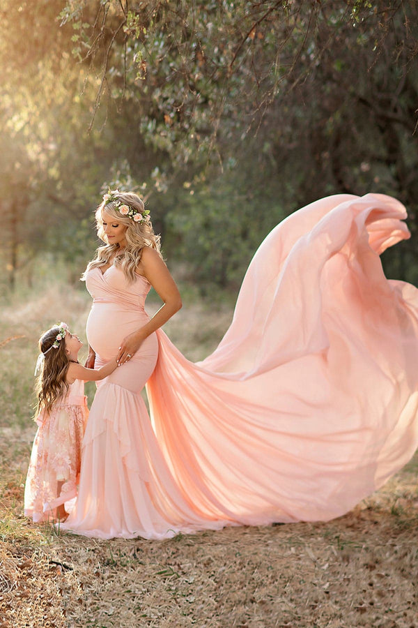 Beautiful pregnant mother wearing the annalise gown and butterfly tossing train standing with her daughter on a forrest path